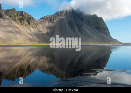 Paesaggio islandese, riflesso della montagna Vestrahorn nelle acque dell'Oceano Atlantico. Penisola Stokksnes, Hofn, Islanda Foto Stock