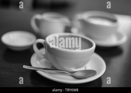 Tazze di caffè con latte caraffa su un tavolo con il bokeh di fondo Foto Stock