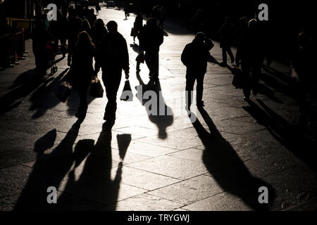 Le ombre lunghe degli acquirenti in un high street a Newcastle upon Tyne, Inghilterra Foto Stock