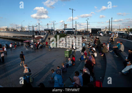 Istanbul, Turchia - 20 settembre, 2018 : una piccola piazza vicino al Ponte di Galata. La gente seduta e appoggiata su scale come sedi. Molte vetture ar passante Foto Stock