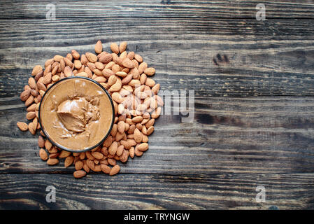 Tutta la mandorla fresca con una ciotola di macinato di fresco cremoso burro di mandorle sopra un tavolo rustico o dello sfondo. Foto Stock