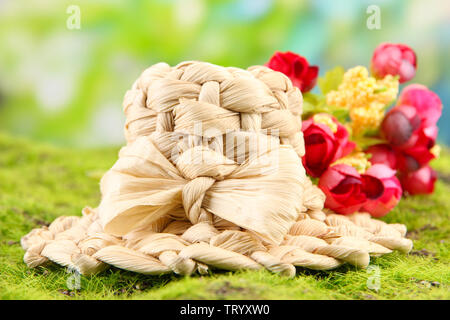 Piccolo cappello di paglia con fiori, sul verde muschio Foto Stock
