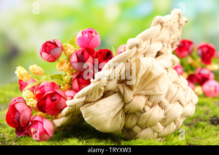 Piccolo cappello di paglia con fiori, sul verde muschio Foto Stock