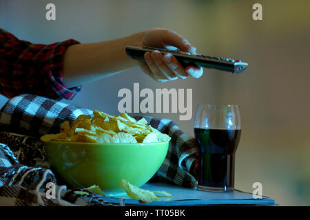 Chi guarda la TV con patatine e cola in camera Foto Stock