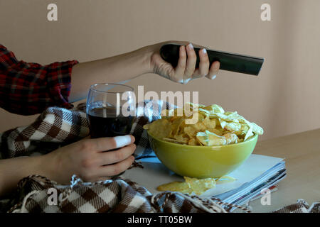 Chi guarda la TV con patatine e cola in camera Foto Stock