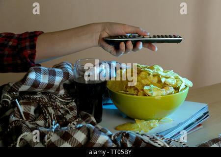 Chi guarda la TV con patatine e cola in camera Foto Stock