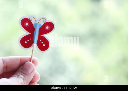 Mano che tiene la carta butterfly Foto Stock