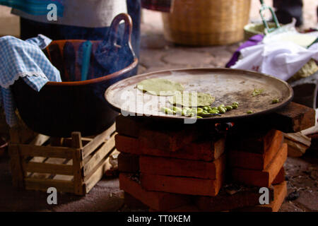 Tortilla di cottura su un messicano tre pietre sparò stufa a legna, mole e fave, rurale scena Foto Stock