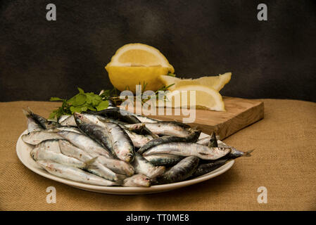 Sarde fresche su un vassoio con le fette di limone Foto Stock