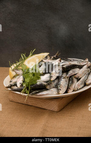 Sarde fresche su un vassoio con le fette di limone Foto Stock