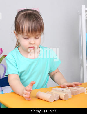 Bambina gioca con la costruzione di blocchi seduta a tavola in camera Foto Stock