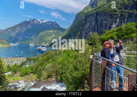 Coppia di mezza età tenendo un selfie presso la cascata Storfossen affacciato sul porto di Geiranger, Møre og Romsdal, Sunnmøre, Norvegia Foto Stock