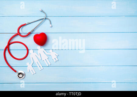 Assicurazione medica concetto. Famiglia intaglio e stetoscopio blu su sfondo di legno Foto Stock