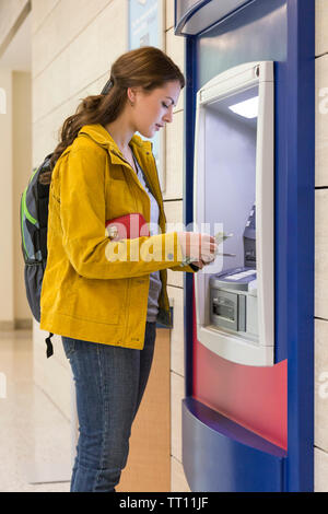 Giovane donna college universitario degli studenti di ottenere denaro contante presso la banca ATM. Finanza personale bancario elettronico concetto. Foto Stock