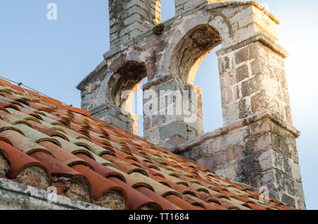 Vecchio rosso tegole sul tetto della chiesa vecchia.contro la torre campanaria.Close up. Foto Stock