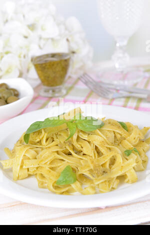 Deliziosi piatti di pasta al pesto sulla piastra su tavola su sfondo chiaro Foto Stock