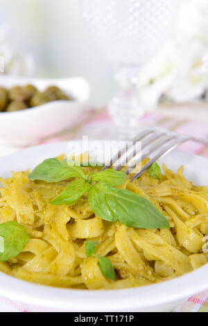 Deliziosi piatti di pasta al pesto sulla piastra su tavola su sfondo chiaro Foto Stock