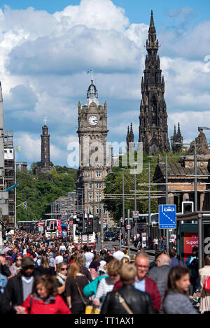 Guardando lungo una trafficata Princes Street, Edimburgo, Scozia. con il Monumento di Scott, Balmoral Hotel e Nelson's Monument in background. Foto Stock