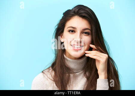 Ritratto di una giovane e bella donna caucasica, felice e sorridente, guardando la telecamera, isolato su sfondo blu Foto Stock