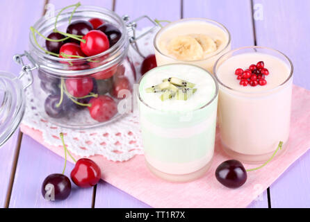 Delizioso yogurt con frutta gusti in bicchieri e frutta fresca sul colore di sfondo in legno Foto Stock