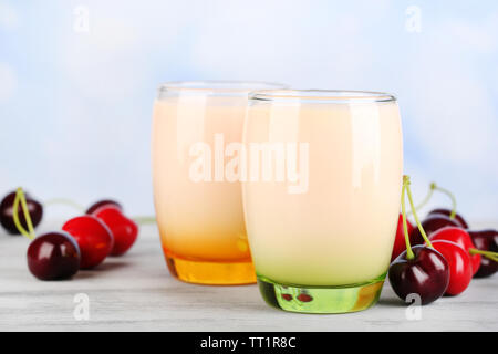 Delizioso yogurt con frutta gusti in bicchieri e frutta fresca sul tovagliolo, sul colore tavolo in legno, su sfondo chiaro Foto Stock