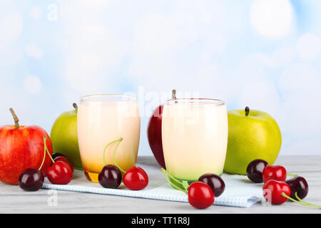 Delizioso yogurt con frutta gusti in bicchieri e frutta fresca sul tovagliolo, sul colore tavolo in legno, su sfondo chiaro Foto Stock