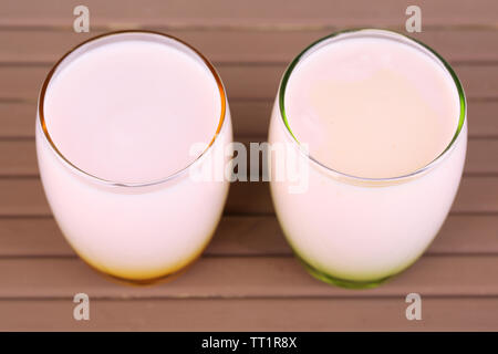 Delizioso yogurt con frutta gusti in bicchieri in legno di colore di sfondo della tabella Foto Stock