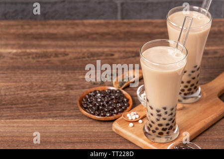 Popolare bevanda Taiwan - Bubble latte tè con tapioca pearl palla nel bicchiere e paglia, tavolo in legno grigio Sfondo mattone, close up, spazio di copia Foto Stock