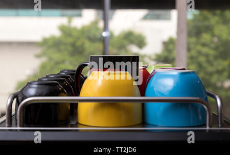 Tazze colorate in una fila in una caffetteria o per la cucina Foto Stock