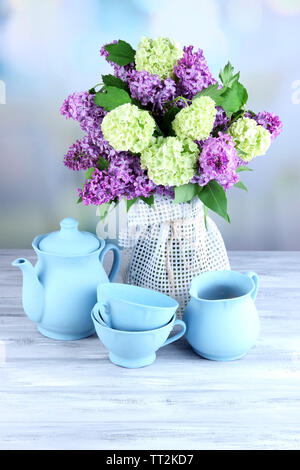 Composizione con set per il tè e bellissimi fiori primaverili in vaso, sul tavolo di legno, su sfondo lucido Foto Stock