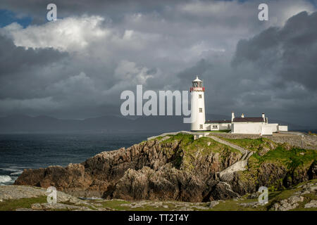 Fanad lighhouse sulle rocce costiere di Donegal Irlanda. Ci sono nuvole temporalesche in background Foto Stock