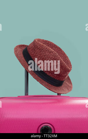 Valigia rosa con hat sul rosa pastello sfondo. concetto di viaggio. Stile minimal. Foto Stock