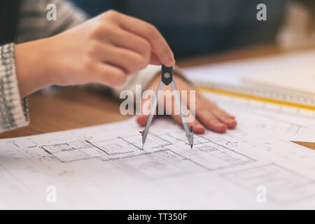 Un architetto con la bussola a disegnare e misurare il disegno del negozio in office Foto Stock