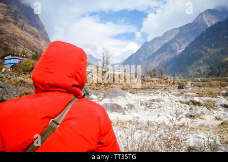 Attivo nepalesi senior bella donna in rosso giacca invernale guardando la montagna e cielo blu sullo sfondo. Momento di relax in attesa del tramonto. Godendo Foto Stock