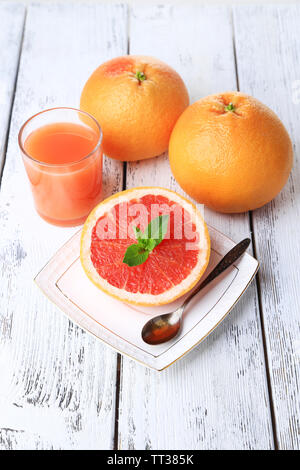 Semi di Pompelmo, bicchiere di succo di frutta fresco e cucchiaio su piastra su sfondo chiaro Foto Stock