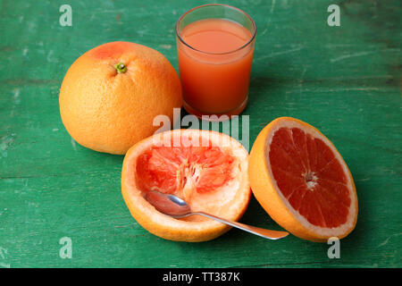 Mature pompelmi e bicchiere di succo di frutta sul colore di sfondo in legno Foto Stock