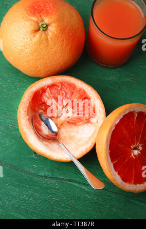 Mature pompelmi e bicchiere di succo di frutta sul colore di sfondo in legno Foto Stock