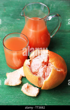 Mature pompelmi e succhi di frutta in vetro sul colore di sfondo in legno Foto Stock