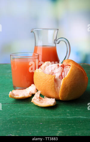 Mature pompelmi e succhi di frutta in vetro sul colore di sfondo in legno Foto Stock