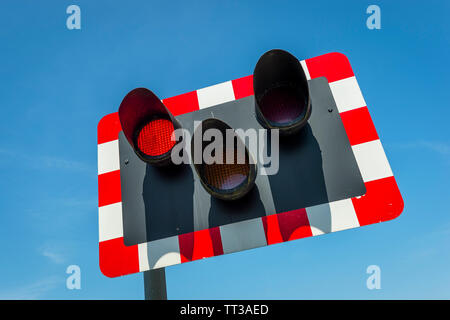 Rosso lampeggiante segnale sull'approccio ad un passaggio a livello ferroviario nel Regno Unito. Foto Stock