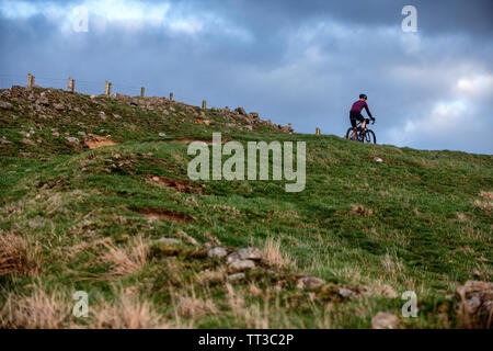 Un uomo che cavalca un touring bike off road nel Parco nazionale di Northumberland. Foto Stock