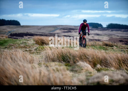 Un uomo che cavalca un touring bike off road nel Parco nazionale di Northumberland. Foto Stock