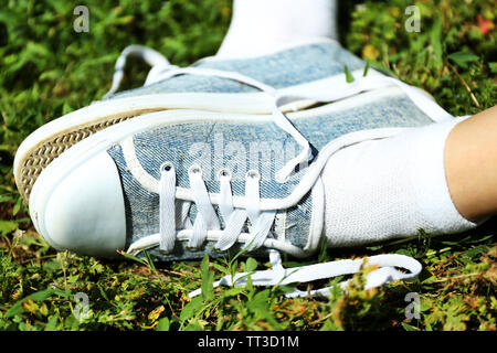Gambe femmina in sneakers in erba verde Foto Stock
