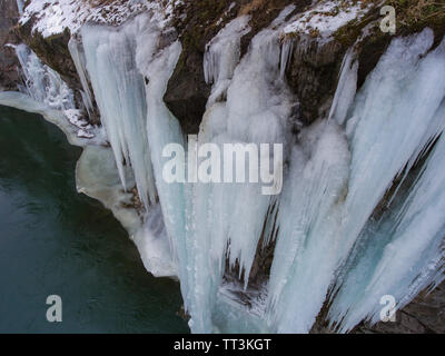 Grandi ghiaccioli appesi da una scogliera congelati di un ruscello di montagna. Foto Stock