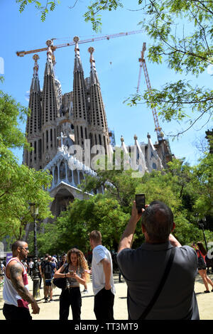 Barcellona/Spagna - 3 Giugno 2019: Maschio azienda turistica su smartphone per scattare una foto della famosa cattedrale Sagrada Familia Foto Stock