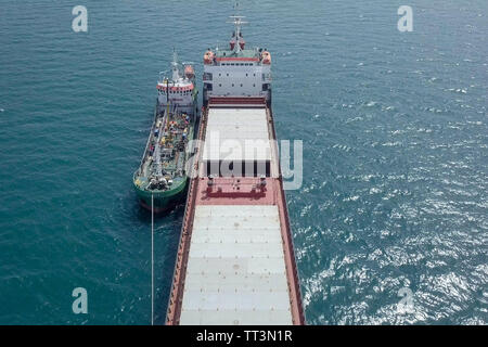 Il rifornimento di carburante in mare - Olio di piccoli prodotti di rifornimento di carburante della nave una grande nave portarinfuse, immagine aerea. Foto Stock