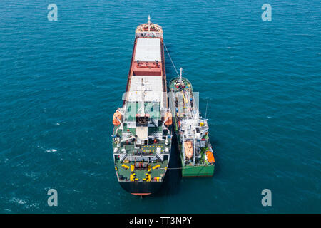 Il rifornimento di carburante in mare - Olio di piccoli prodotti di rifornimento di carburante della nave una grande nave portarinfuse, immagine aerea. Foto Stock