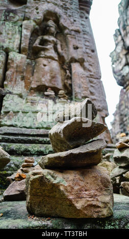 Close-up di una pila di pietre con significato religioso e una offuscata la scultura antica in background, girato in un bellissimo tempio Bayon - un decorat Foto Stock