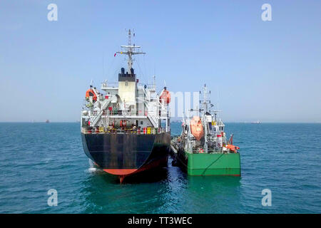 Il rifornimento di carburante in mare - Olio di piccoli prodotti di rifornimento di carburante della nave una grande nave portarinfuse, immagine aerea. Foto Stock