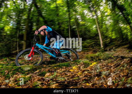 Un uomo corse in mountain bike sulla velocità di un sentiero attraverso il bosco in prossimità della città di Bristol nel sud ovest dell'Inghilterra. Foto Stock